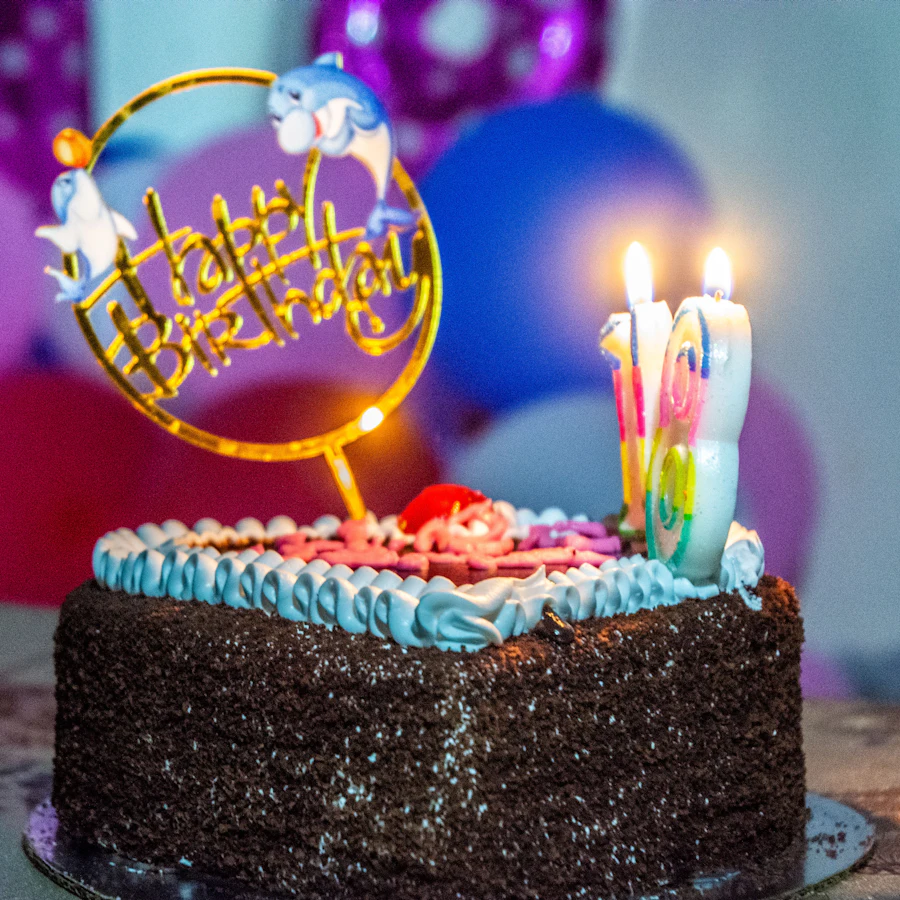 Üzerinde yanan mumlar ve "Happy Birthday" süslemesi olan çikolatalı doğum günü pastası